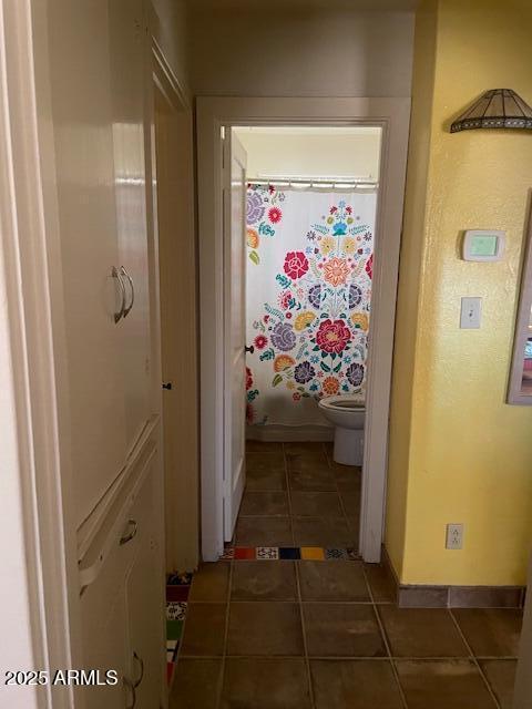 full bath with toilet, curtained shower, baseboards, and tile patterned floors