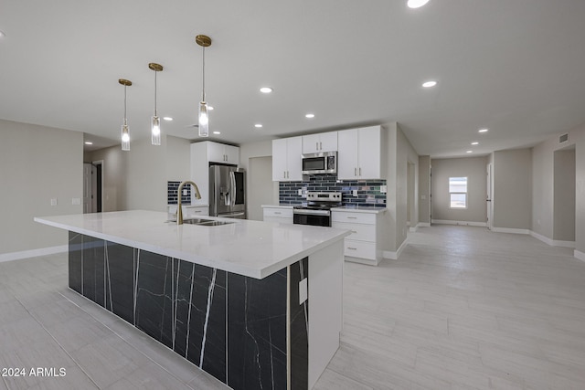 kitchen featuring a large island, white cabinets, sink, decorative light fixtures, and stainless steel appliances