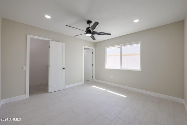 unfurnished bedroom with a spacious closet, a closet, and ceiling fan