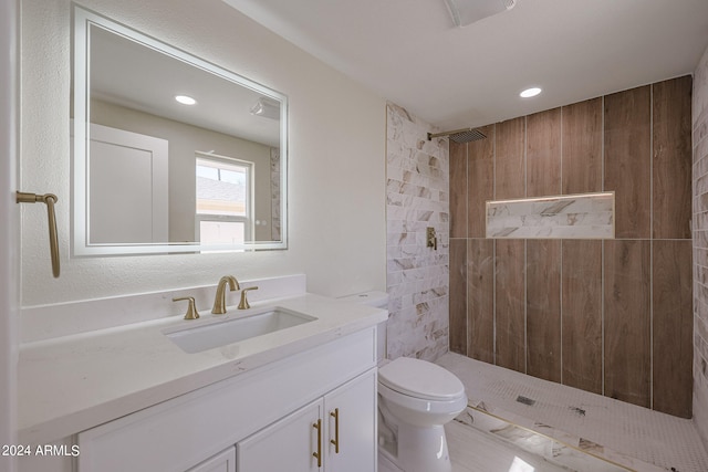 bathroom with vanity, tiled shower, and toilet