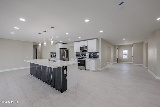 kitchen with hanging light fixtures, a center island with sink, appliances with stainless steel finishes, white cabinetry, and sink