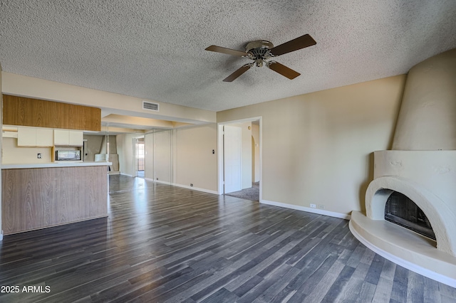 10410 N Cave Creek Rd Unit 2220, Phoenix, AZ 85020 - unfurnished living room with dark wood-type flooring, a ceiling fan, baseboards, a textured ceiling, and a large fireplace