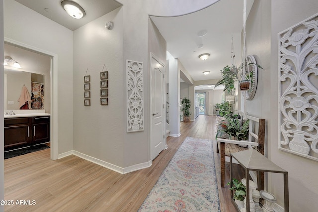 corridor with sink and light hardwood / wood-style flooring