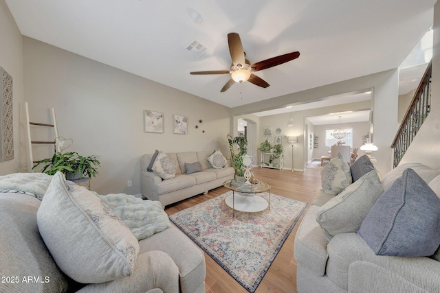 living room with ceiling fan with notable chandelier and light hardwood / wood-style flooring