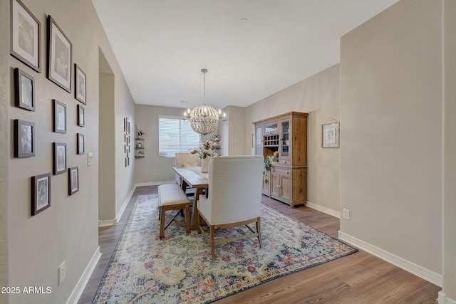 dining area featuring wood-type flooring and an inviting chandelier