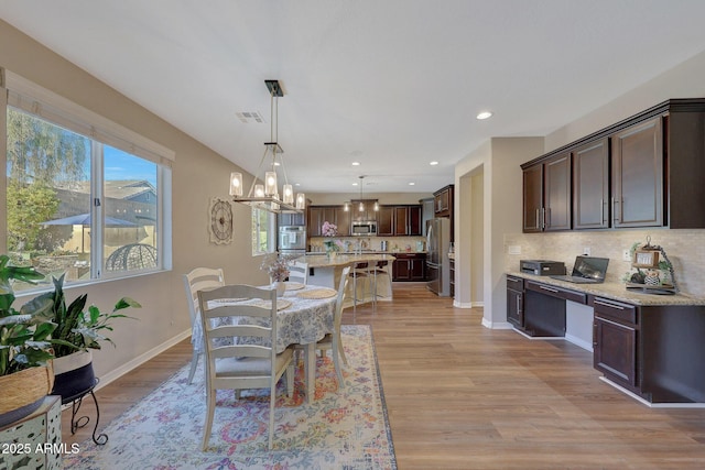 dining area with built in desk and light wood-type flooring