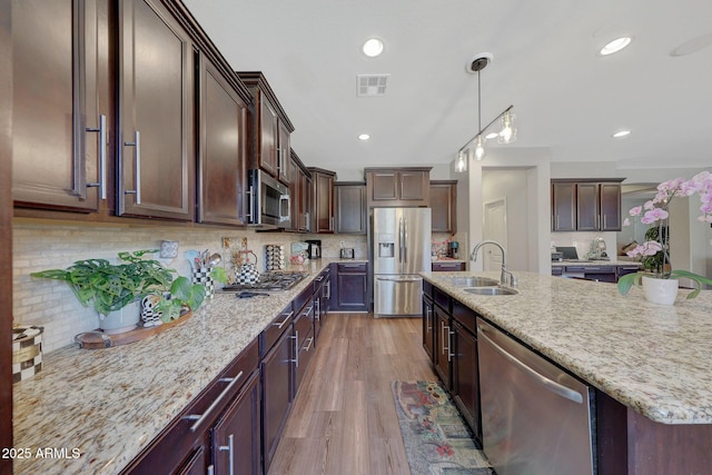 kitchen featuring pendant lighting, light stone countertops, appliances with stainless steel finishes, and sink