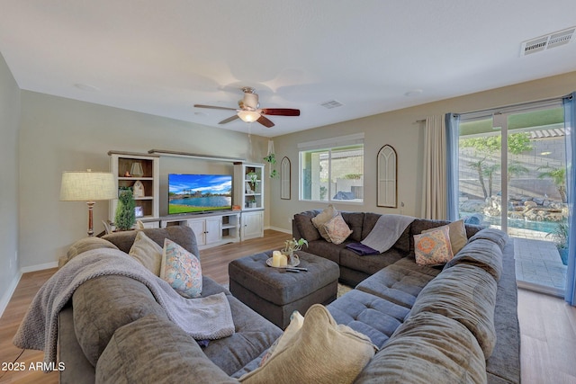 living room featuring ceiling fan, light wood-type flooring, and a wealth of natural light