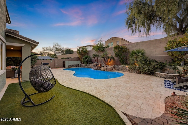 pool at dusk with a patio area