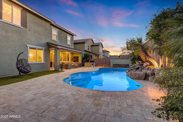 pool at dusk featuring an outdoor living space and a patio