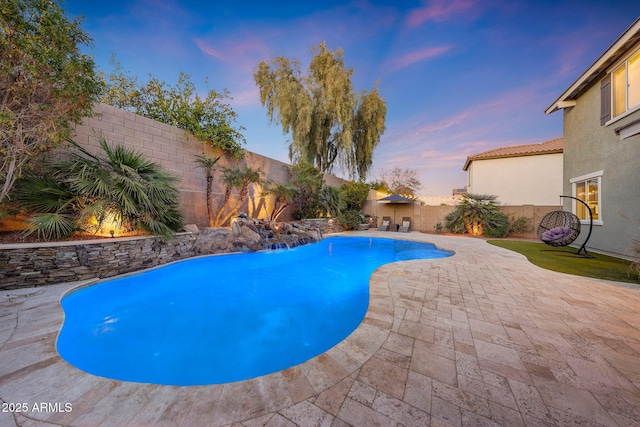 pool at dusk with a patio area