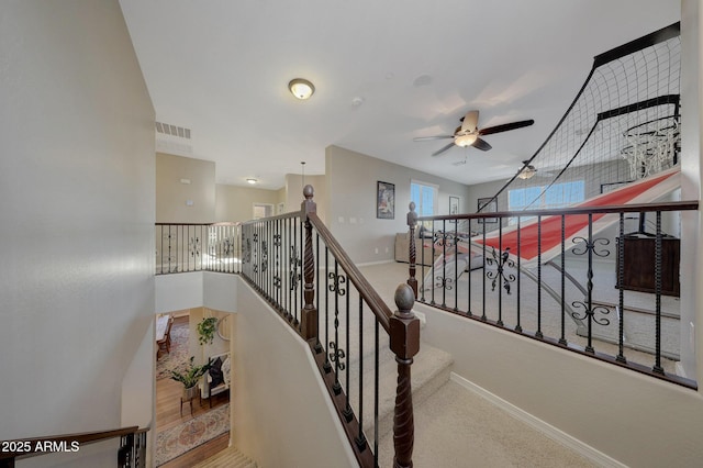 stairs featuring ceiling fan and carpet floors