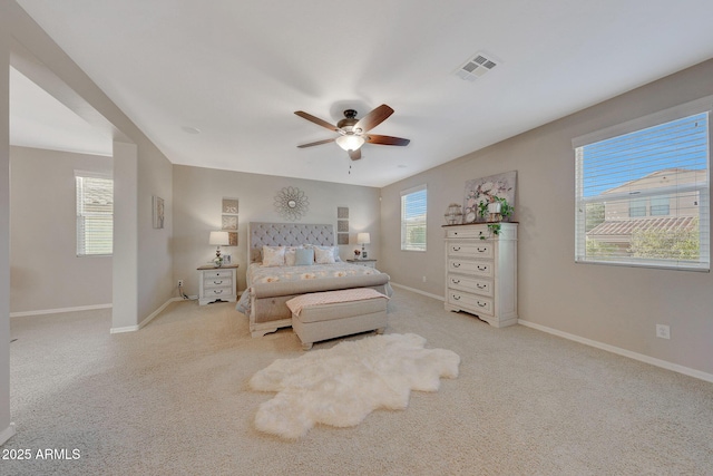 bedroom featuring light carpet, multiple windows, and ceiling fan