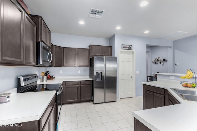 kitchen featuring sink, dark brown cabinetry, light tile patterned floors, and appliances with stainless steel finishes