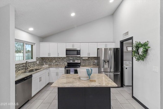 kitchen featuring a kitchen island, washer / dryer, sink, white cabinets, and stainless steel appliances