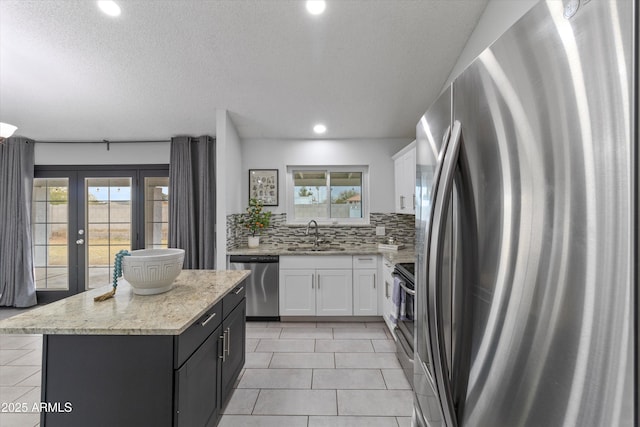 kitchen featuring sink, white cabinetry, a center island, stainless steel appliances, and backsplash