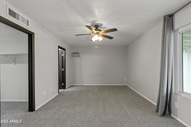 unfurnished bedroom with a closet, carpet floors, an AC wall unit, and ceiling fan