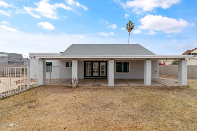 rear view of house featuring a lawn and a patio