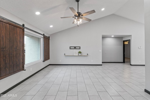 unfurnished living room featuring a barn door, lofted ceiling, a textured ceiling, and ceiling fan