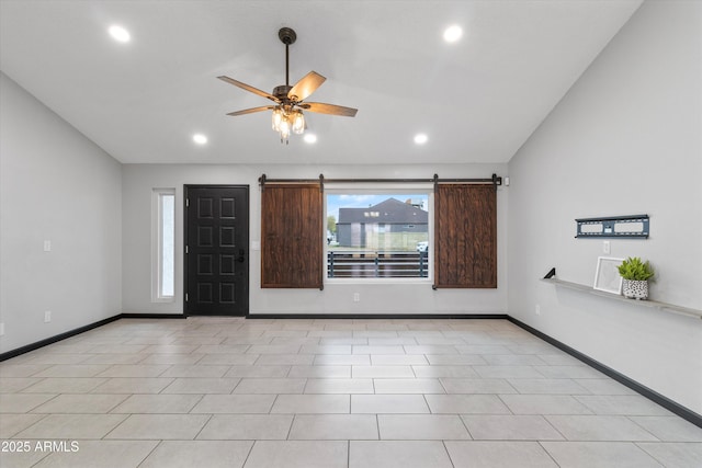 spare room featuring ceiling fan, a barn door, vaulted ceiling, and light tile patterned floors