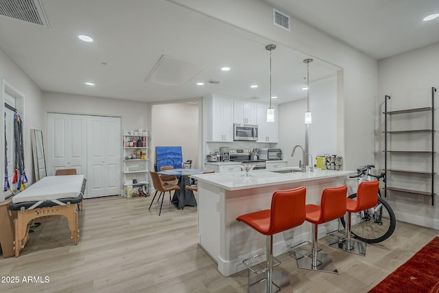 2038 E River Rd Unit 101, Tucson, AZ 85718 - kitchen featuring appliances with stainless steel finishes, a sink, light wood-style floors, white cabinetry, and recessed lighting