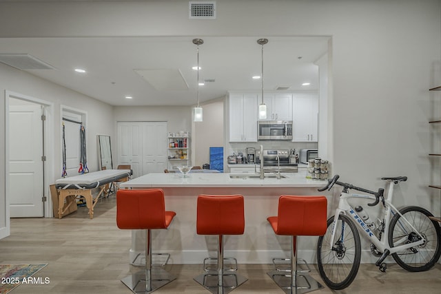 2038 E River Rd Unit 101, Tucson, AZ 85718 - kitchen with appliances with stainless steel finishes, a breakfast bar area, white cabinetry, a sink, and recessed lighting