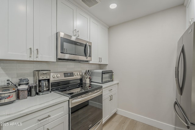 2038 E River Rd Unit 101, Tucson, AZ 85718 - kitchen featuring appliances with stainless steel finishes, baseboards, backsplash, light wood-type flooring, and white cabinets