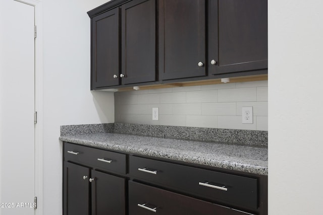 kitchen with stone counters, tasteful backsplash, and dark brown cabinetry