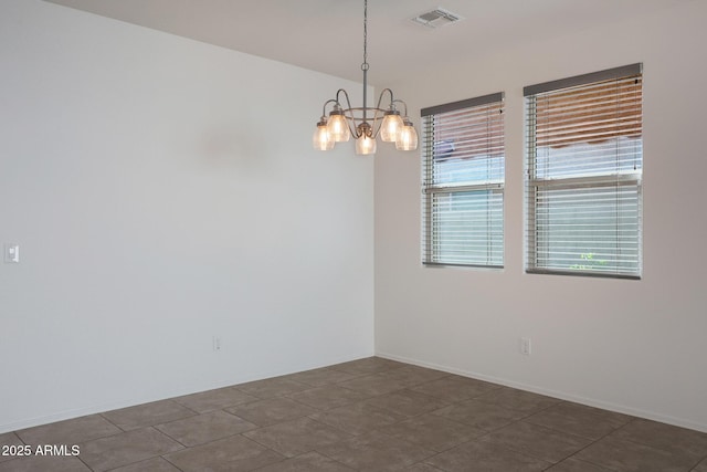 tiled spare room featuring a notable chandelier