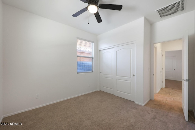 unfurnished bedroom with ceiling fan, a closet, and light carpet