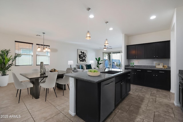 kitchen featuring sink, dishwasher, ceiling fan with notable chandelier, hanging light fixtures, and a kitchen island with sink