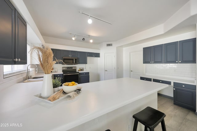 kitchen featuring stainless steel microwave, electric stove, a sink, a breakfast bar area, and a peninsula