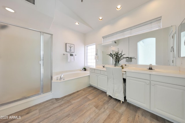 full bathroom with a sink, a shower stall, two vanities, a garden tub, and wood finished floors