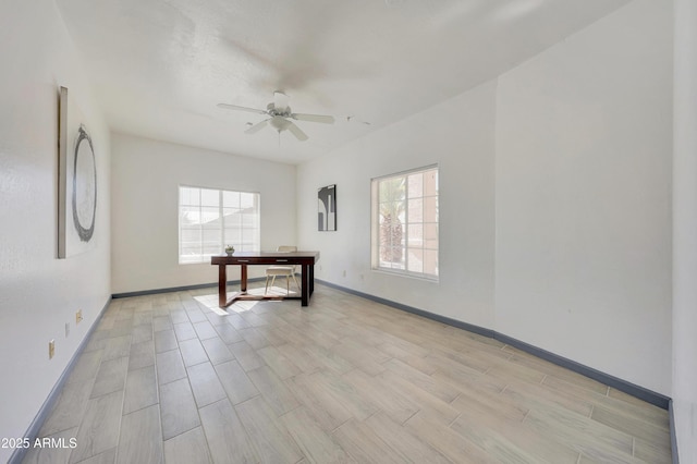 spare room with light wood-type flooring, a ceiling fan, and baseboards