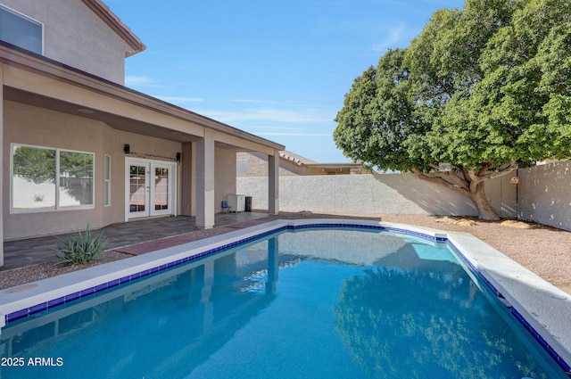 view of swimming pool featuring a fenced in pool, a fenced backyard, french doors, and a patio area