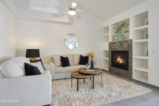 living room with built in features, a ceiling fan, a stone fireplace, visible vents, and lofted ceiling