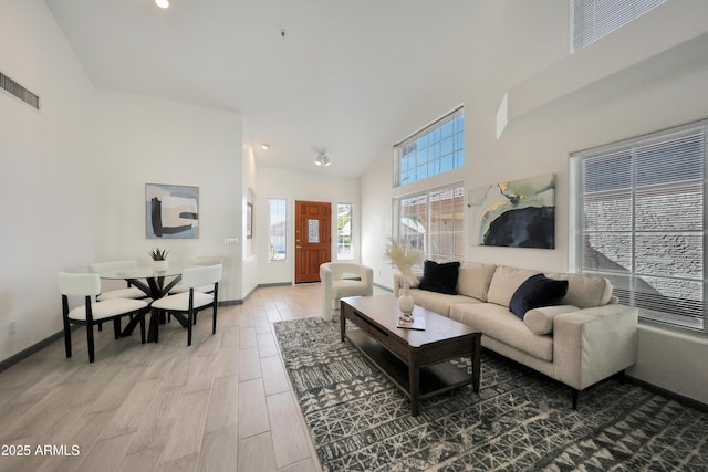 living room featuring light wood finished floors, recessed lighting, high vaulted ceiling, visible vents, and baseboards