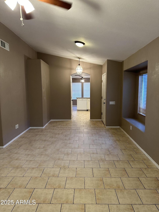 tiled empty room featuring vaulted ceiling and ceiling fan