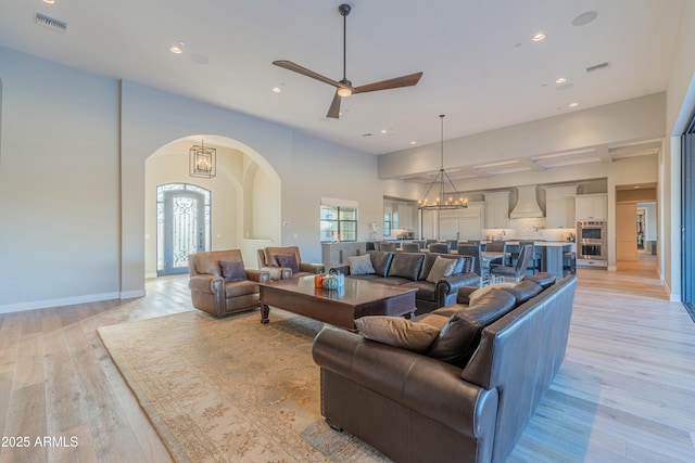 living room with ceiling fan with notable chandelier and light wood-type flooring