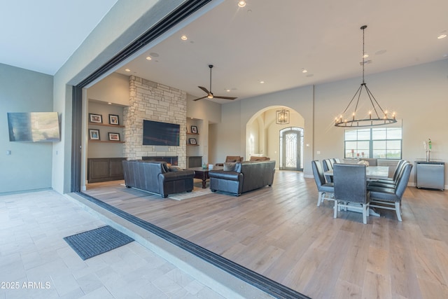 living room with ceiling fan with notable chandelier, a fireplace, and light hardwood / wood-style floors