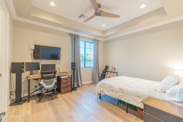 bedroom featuring ornamental molding, a tray ceiling, and light wood-type flooring