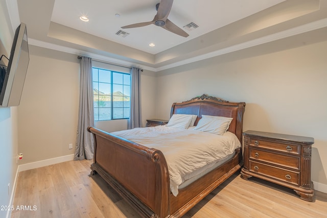 bedroom featuring a raised ceiling, ceiling fan, and light hardwood / wood-style floors