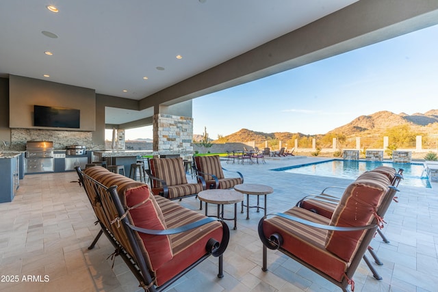 view of patio with a community pool, exterior bar, a grill, exterior kitchen, and a mountain view