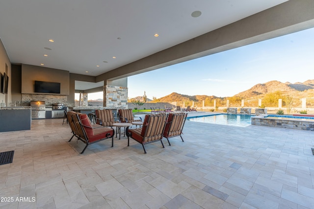 view of patio / terrace featuring area for grilling, exterior bar, and a pool with hot tub