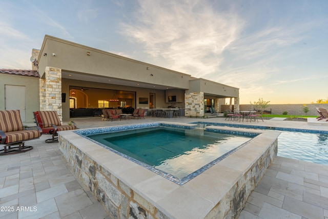 pool at dusk featuring a patio area and a hot tub