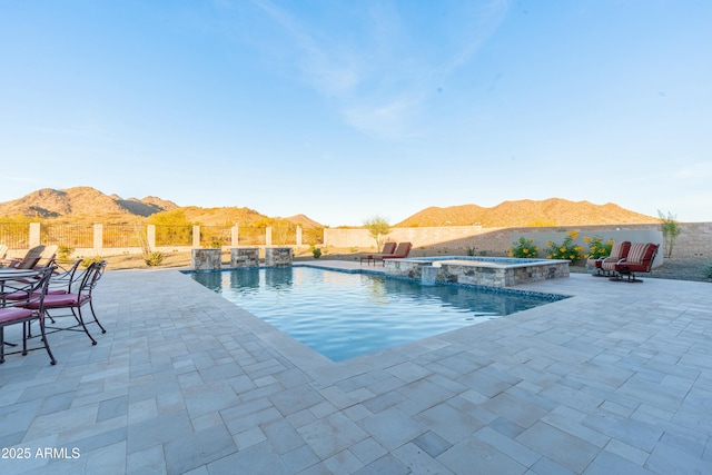 view of swimming pool featuring an in ground hot tub, a mountain view, and a patio