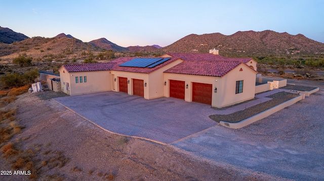 view of front facade with a mountain view, a garage, and solar panels