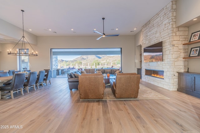 living room featuring a stone fireplace, wood-type flooring, and a chandelier