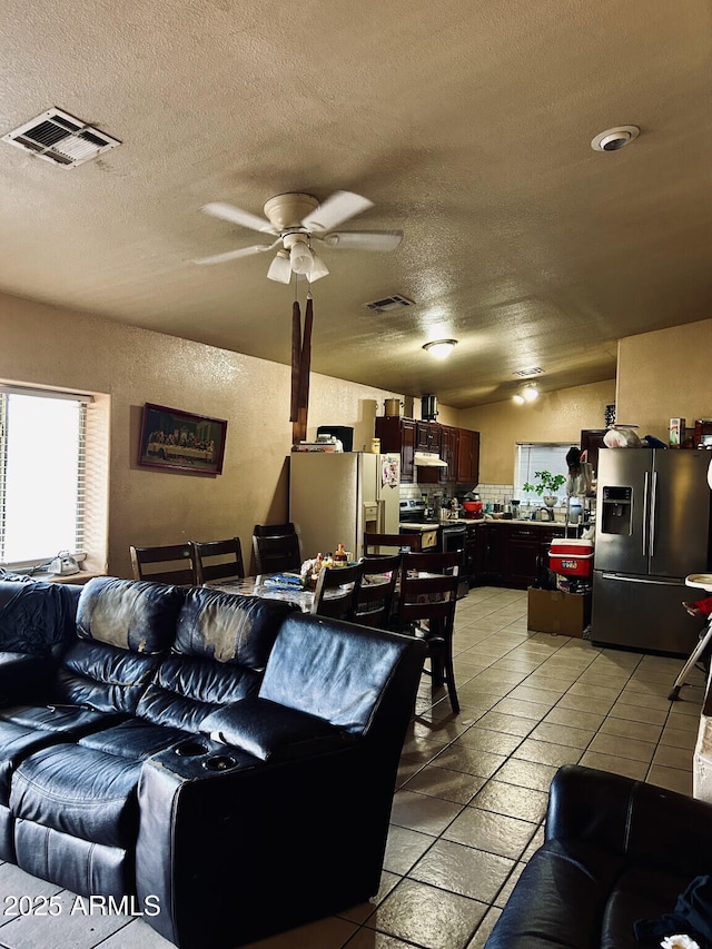 tiled living room with lofted ceiling, a textured ceiling, and ceiling fan