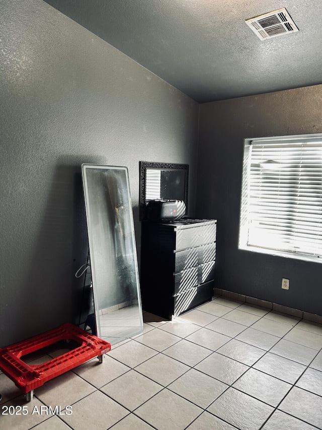 bedroom with light tile patterned floors and a textured ceiling